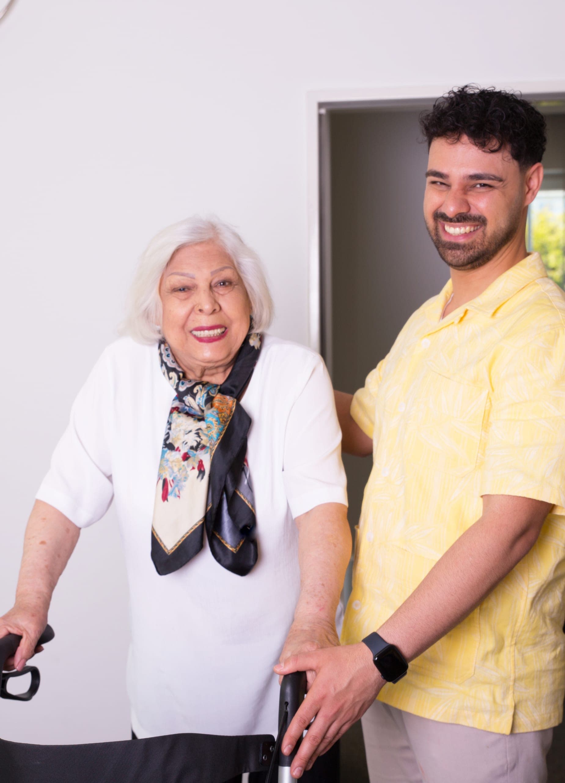 Pflegekraft unterstützt eine Seniorin mit Rollator