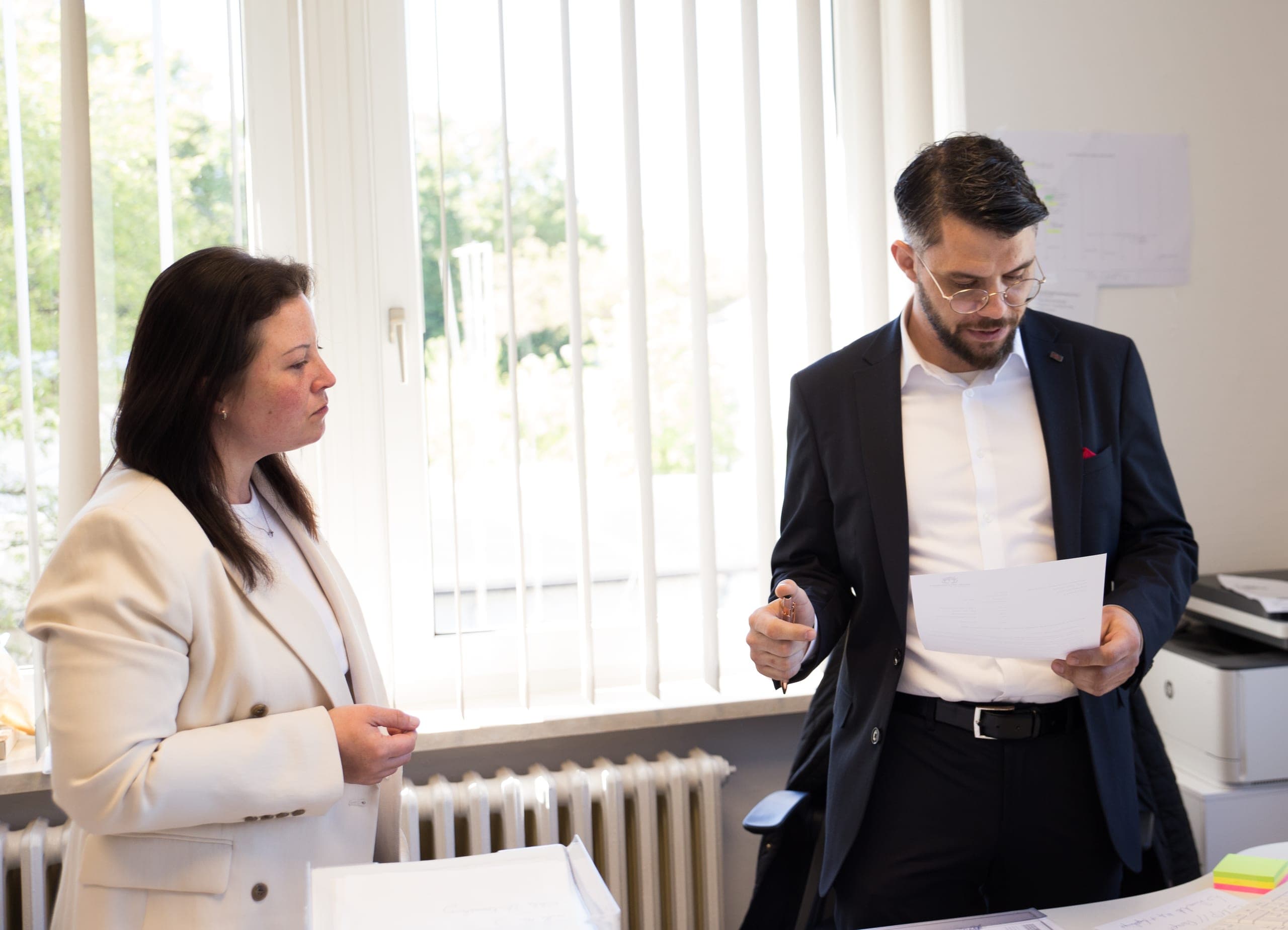 Zwei Mitarbeitende von Engel Pflegedienst gehen im Büro gemeinsam ein Schreiben durch